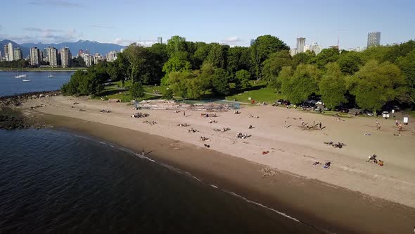People Enjoying The Reopened Kitsilano Beach During Summer With Downtown Skyline And English Bay Bea