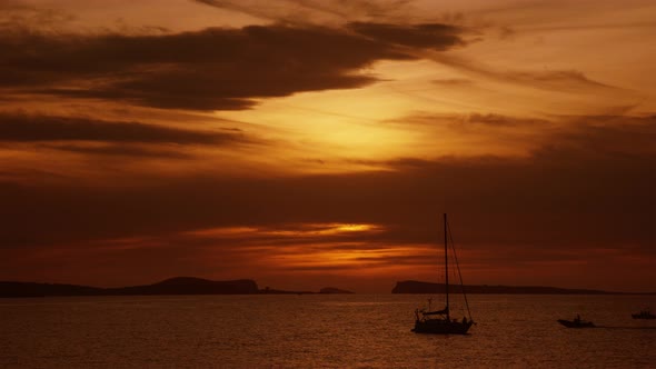 Golden Sunset by the Sea with Two small Boats going past with Island Mountains in the Background 