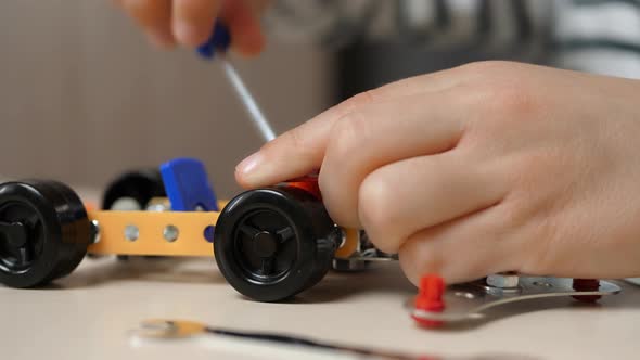 A Small Boy Builds a Car Model From a Metal Construction Kit, Twisting the Parts. Close-up of the