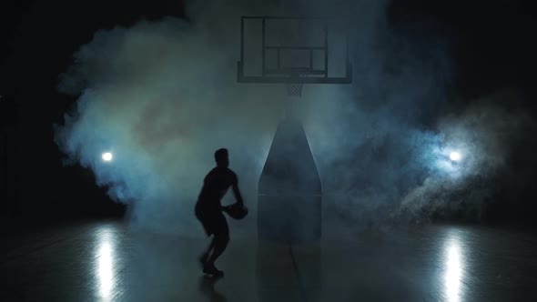 Basketball Jump - Dark Silhouette of a Man. Black Background in Cloud of Smoke.