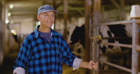 Confident Mature Male Farmer Holding Pitchfork in Stable