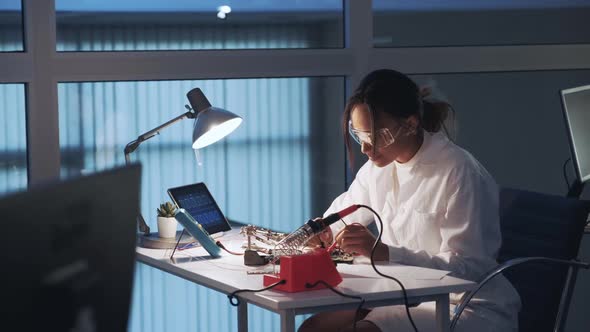 African American Electronics Specialist Making Tests on Electronic Board with Multimeter Tester in