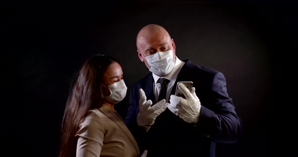 Portrait of a Couple on a Black Background. They Put on Disposable Masks and Protective Gloves