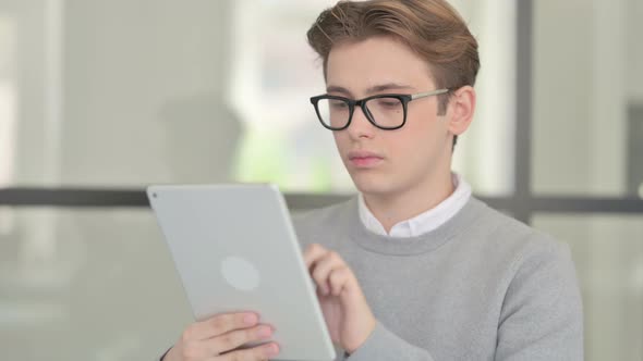 Attractive Young Man Using Tablet in Modern Office