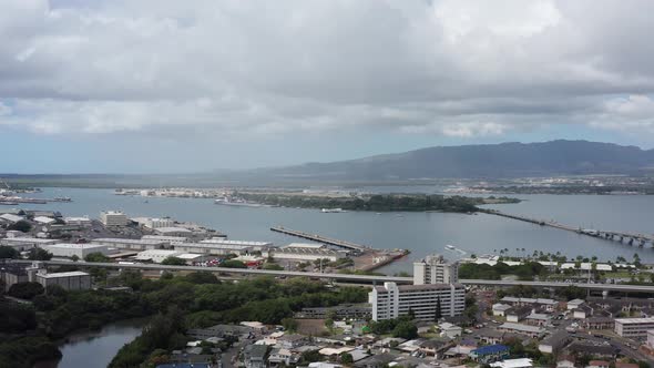 Aerial wide dolly shot of Pearl Harbor with the USS Arizona Memorial in the background on the island