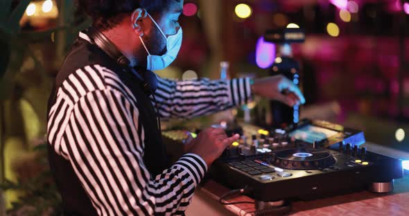 Black Dj playing music at cocktail bar outdoor while wearing face safety mask