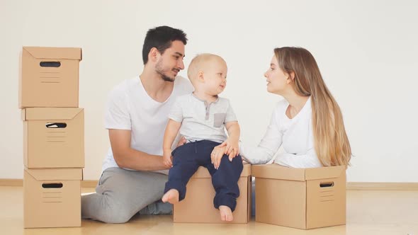 Family with Boy Unpacking Moving Cardboard Boxes at New Home