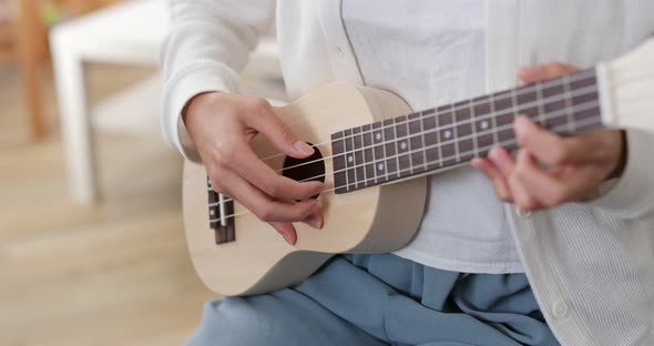 Woman play ukulele at home