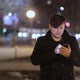 A man against the background of night lights is typing text on a smartphone . - VideoHive Item for Sale