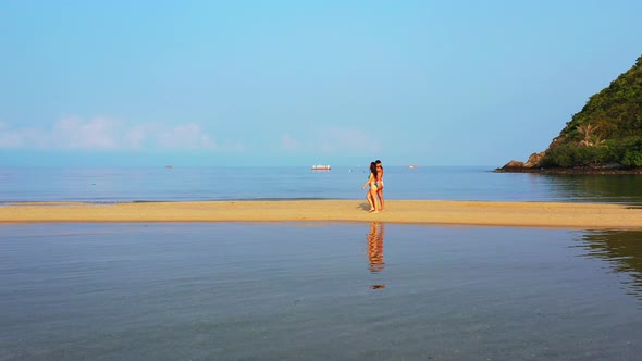 Modern smiling girls on holiday in the sun at the beach on paradise white sand and blue background