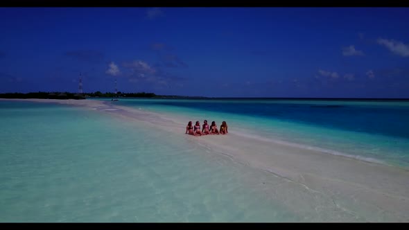 Women relaxing on paradise lagoon beach trip by blue lagoon and white sandy background of the Maldiv