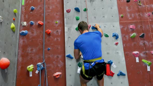 Man practicing rock climbing in fitness studio 4k