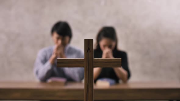 A young Asian Christian couple praying to Jesus Christ in a church.