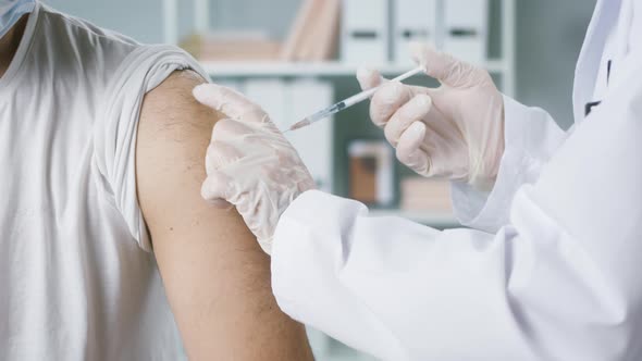 Coronavirus Vaccination Closeup Grafting in Polyclinic Doctor in Protective Suit Giving Injection