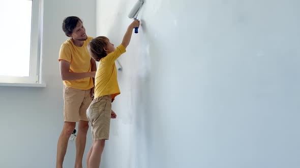 A Father and Son Both Wearing a Yellow Tshirt Paint the Wall Using a Roller Painter