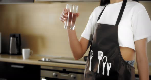 Young Pretty Woman Drinks Water From Glass in the Kitchen