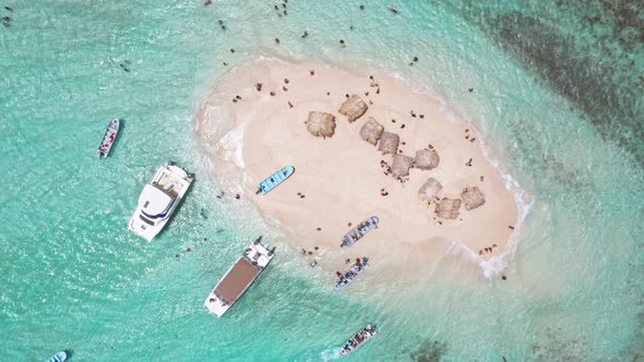 Packed tourist boats descend on small tropical coral islet in Caribbean; drone