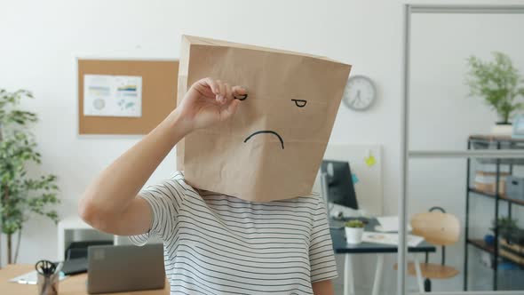 Portrait of Woman Wearing Sad Emoji Paper Bag Crying Wiping Tears Standing in Office Alone