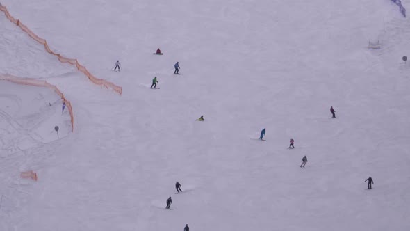 Skiers and Snowboarders Ride on a Snowy Slope at a Ski Resort in Sunny Day