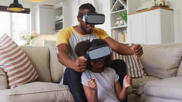 African american daughter and her father playing game wearing vr headsets