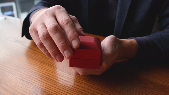 a Man's Hands Open a Box with a Wedding Ring