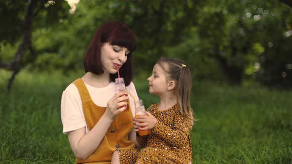 Close Up Portrait of Single Mom with Little Daughter is Engaged in Drinking Juice