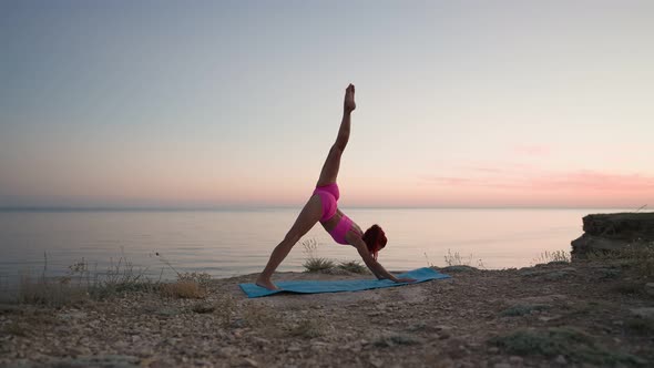 Athletic Fitness Woman Doing Yoga on the Background of Sunset Sea and Rocks