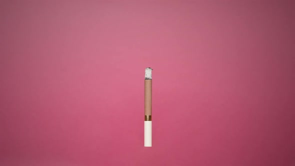 A Cigarette Smolders On Pink Background