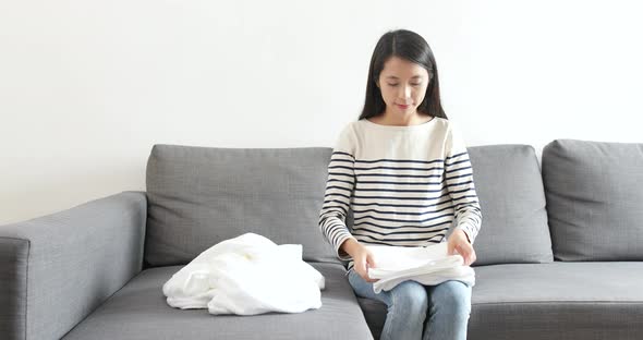 Housewife doing housework of folding white towel at home