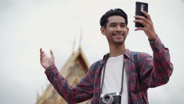 Asian man solo tourists standing using smartphones video chat with friends on the street.