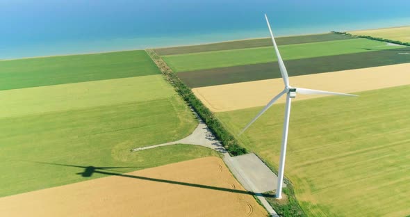 Windmill for electric power production in the agricultural fields. Aerial view.