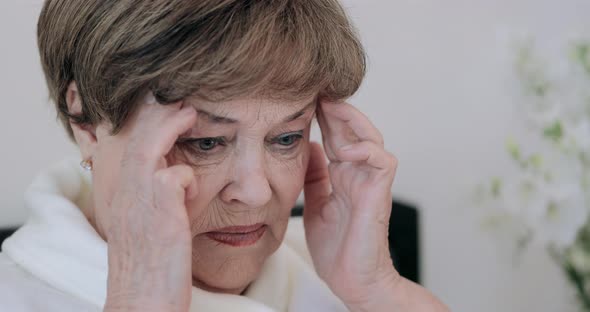 Close Up View of Elderly Woman in 70s Having Terrible Headache and Massaging Head, Mature Lady 