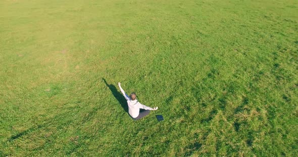 Low Orbital Flight Around Man on Green Grass with Notebook Pad at Yellow Rural Field.