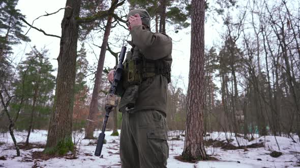 Side View of Brave Ukrainian Soldier Putting on Sunglasses Standing in Winter Forest and Looking at