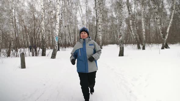 Mature Woman Is Running Through The Forest In A Winter Day