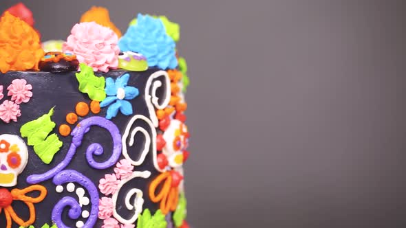 Gourmet Dia de los Muertos cake decorated with colorful buttercream frosting and gummy cupcake toppe