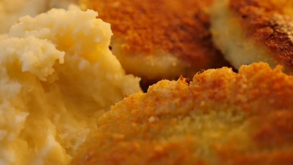 Puree of mashed potato and fish fried  burgers on plate 4K 2160p 30fps UltraHD video - Slow tilt ove