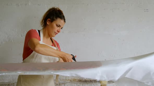 Woman cutting fabric for surfboard