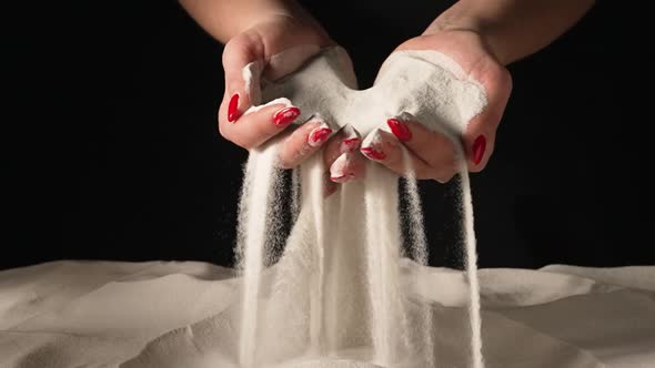 Women's Hands Picking Up Sand in Their Palms and Spilling Grains of Sand Through Their Fingers