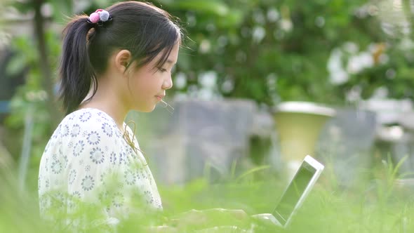 Beautiful Asian Girl  Sitting In Park On The Green Grass With Laptop