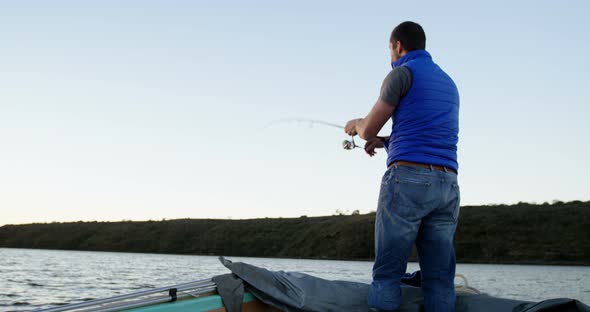 Man fishing while standing on motorboat 4k