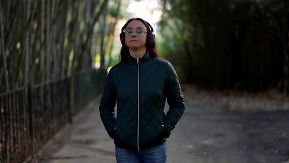 Carefree Woman is Walking in Park and Listening to Music By Headphones Enjoying Good Mood