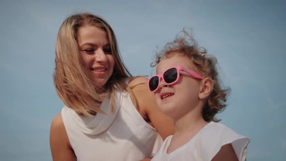 Happy Mother and Daughter are Resting in a City Park on a Bench