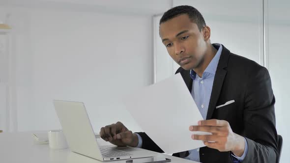 Casual AfroAmerican Businessman Working on Documents and Laptop