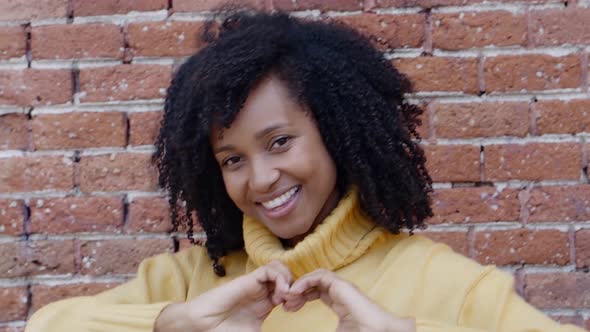 Cheerful Young Brazilian Woman Makes a Heart with Her Hands