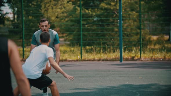 Young Man Playing Basketball on the Sports Ground with Friends - Dribbling, Avoiding His Opponents
