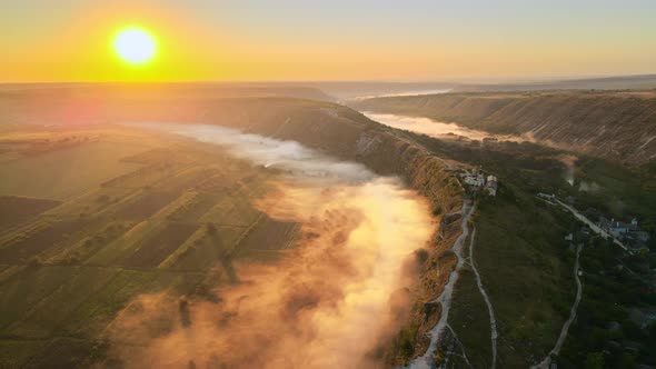Aerial drone view of the Old Orhei at sunset. Valley with river and fog, village, monastery located 