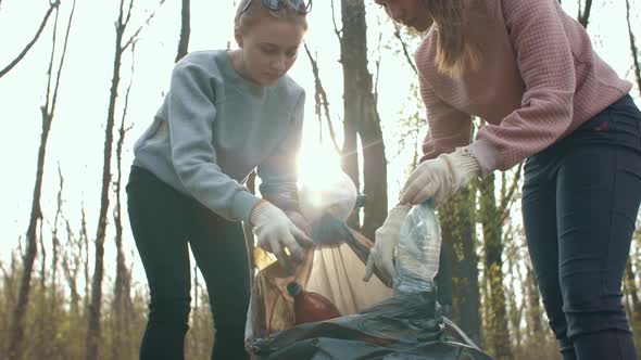 Two Women Putting Old Plastic Bottles in a Trash Bag