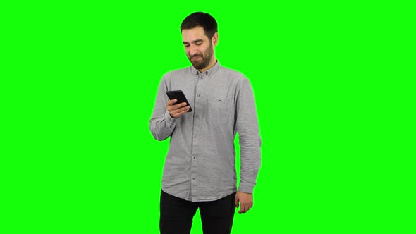 Brunette Guy Is Texting on His Phone and Smiling. Green Screen