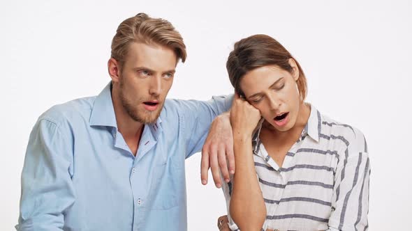 Young Caucasian Pair Yawning on White Background and Fighting Sleep in Slowmotion